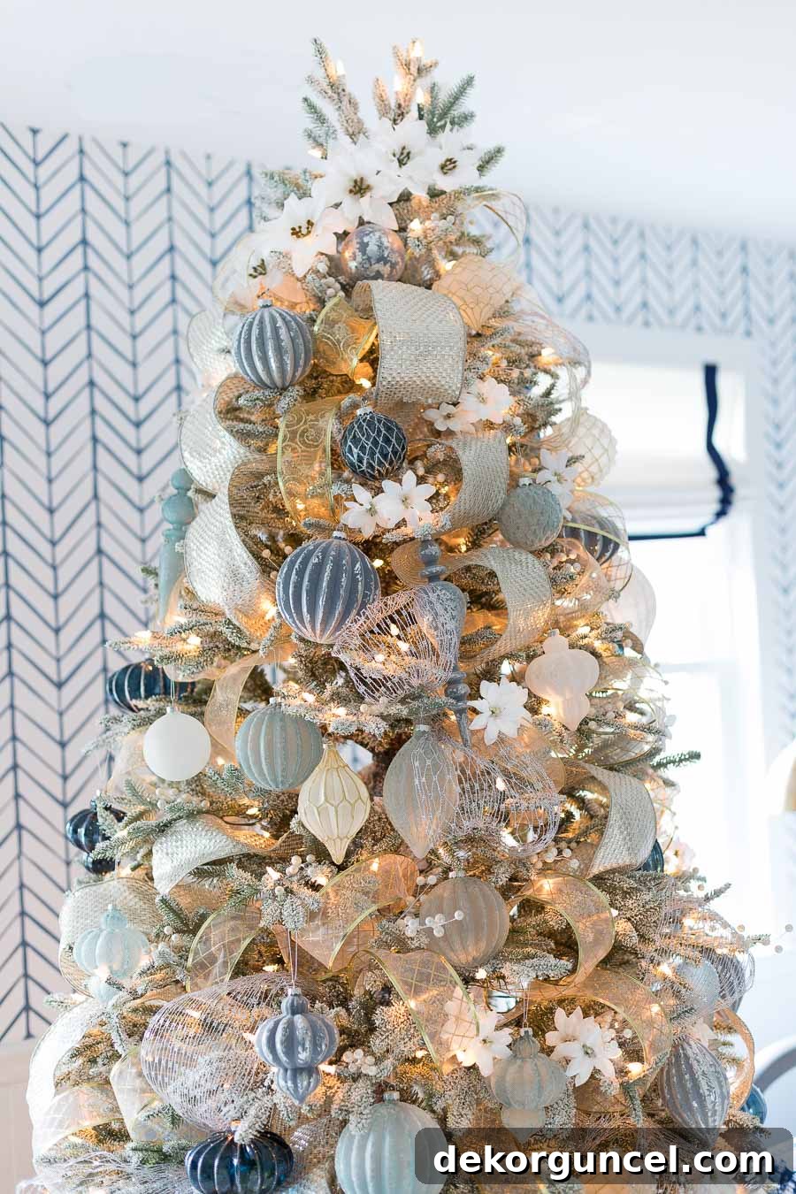 Faux white poinsettias gracefully spiraling up a Christmas tree, serving as a unique and elegant alternative to a traditional tree topper