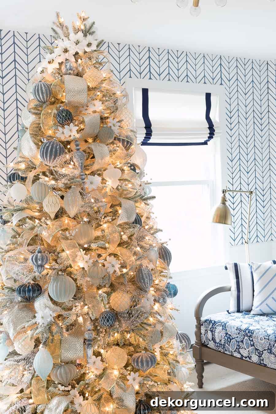 Gorgeous Christmas tree elegantly decorated in blue, white, silver, and gold with delicate white poinsettia accents, creating a harmonious holiday display