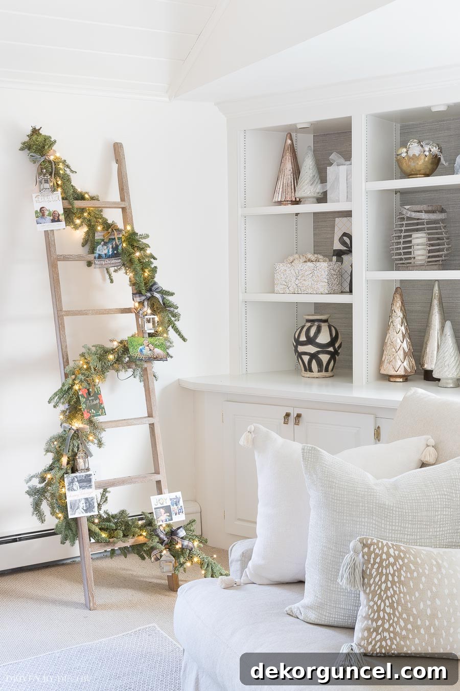 Creative Christmas card display using a ladder wrapped with garland and fairy lights, adorned with cards and mini lanterns