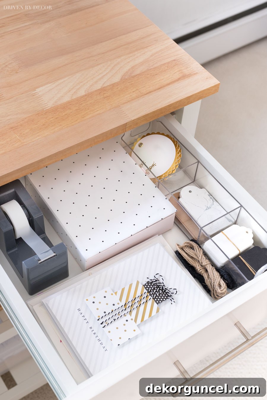 A drawer of a gift wrapping station, neatly organized with tape dispenser, greeting cards, and gift tags, ready for use.