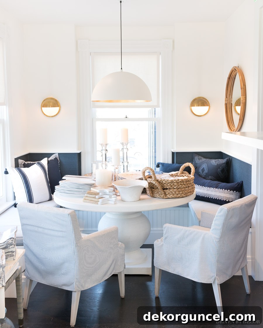 A stunning built-in banquette area with blue and white decor, beautifully accented by navy grasscloth wallpaper for added texture and color.
