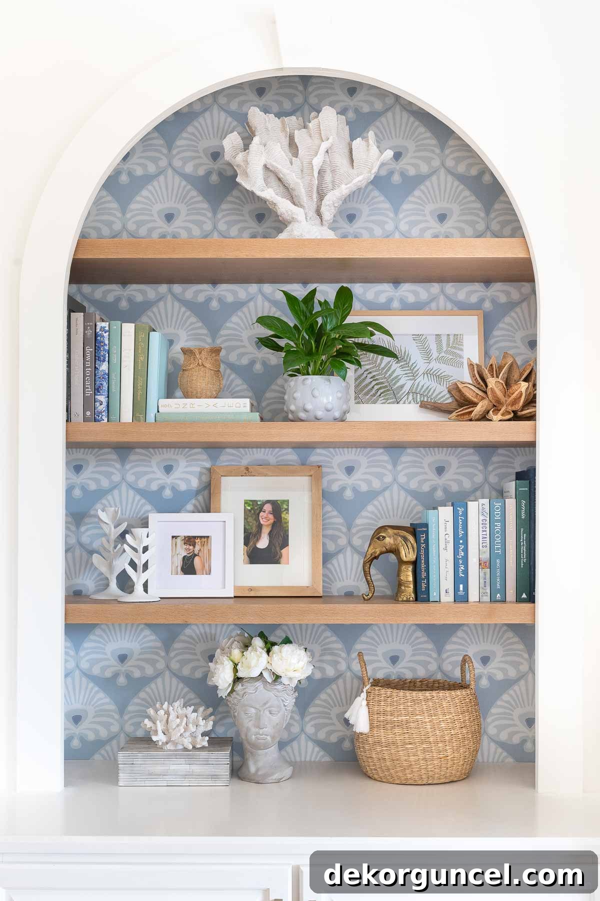 Bookshelf decor on oak shelves with the stunning Palmetto wallpaper on the back of the bookcase, creating a verdant and refined botanical backdrop.
