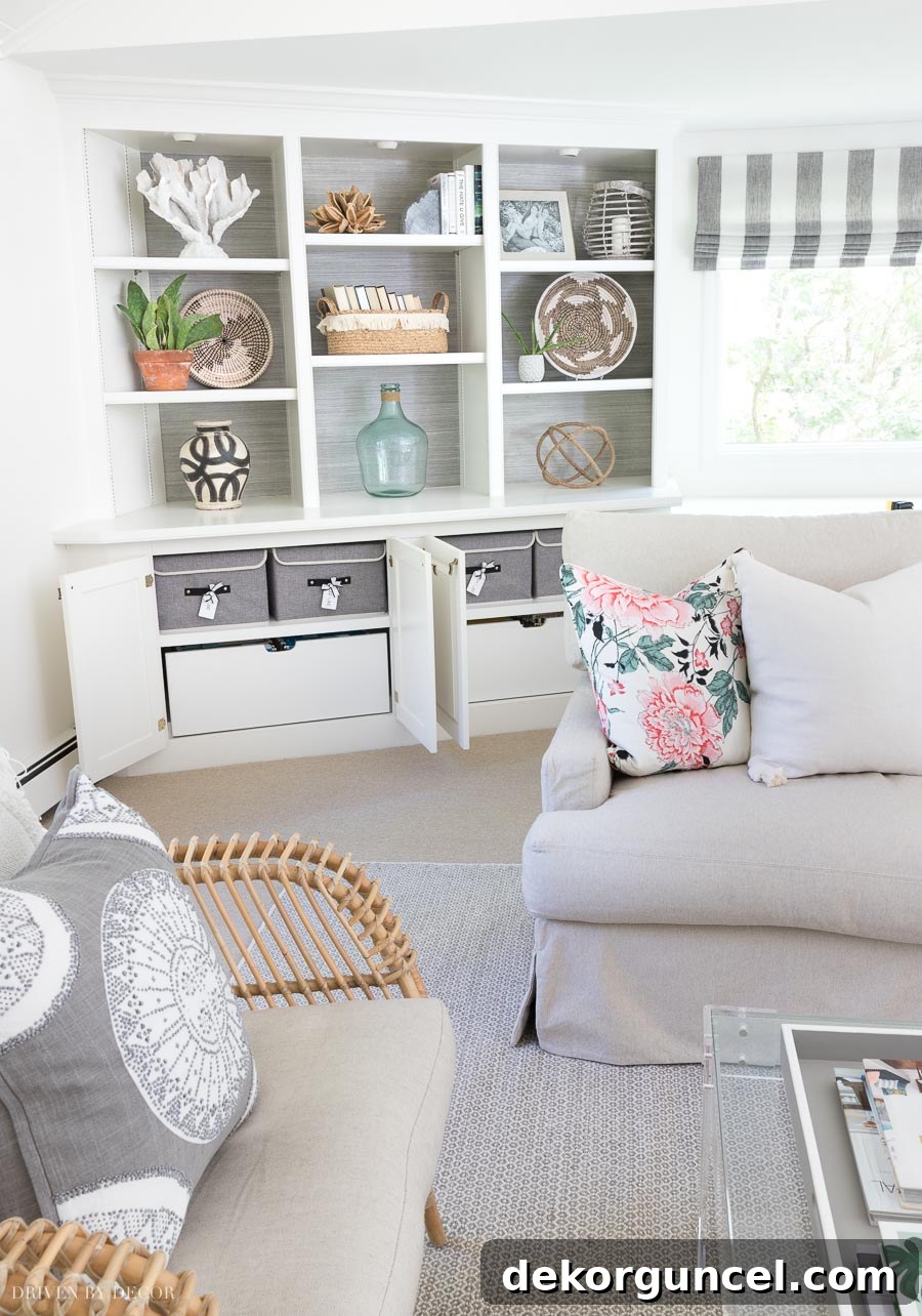 Fabric storage boxes for pillow covers neatly arranged inside the base cabinets of a family room bookcase.