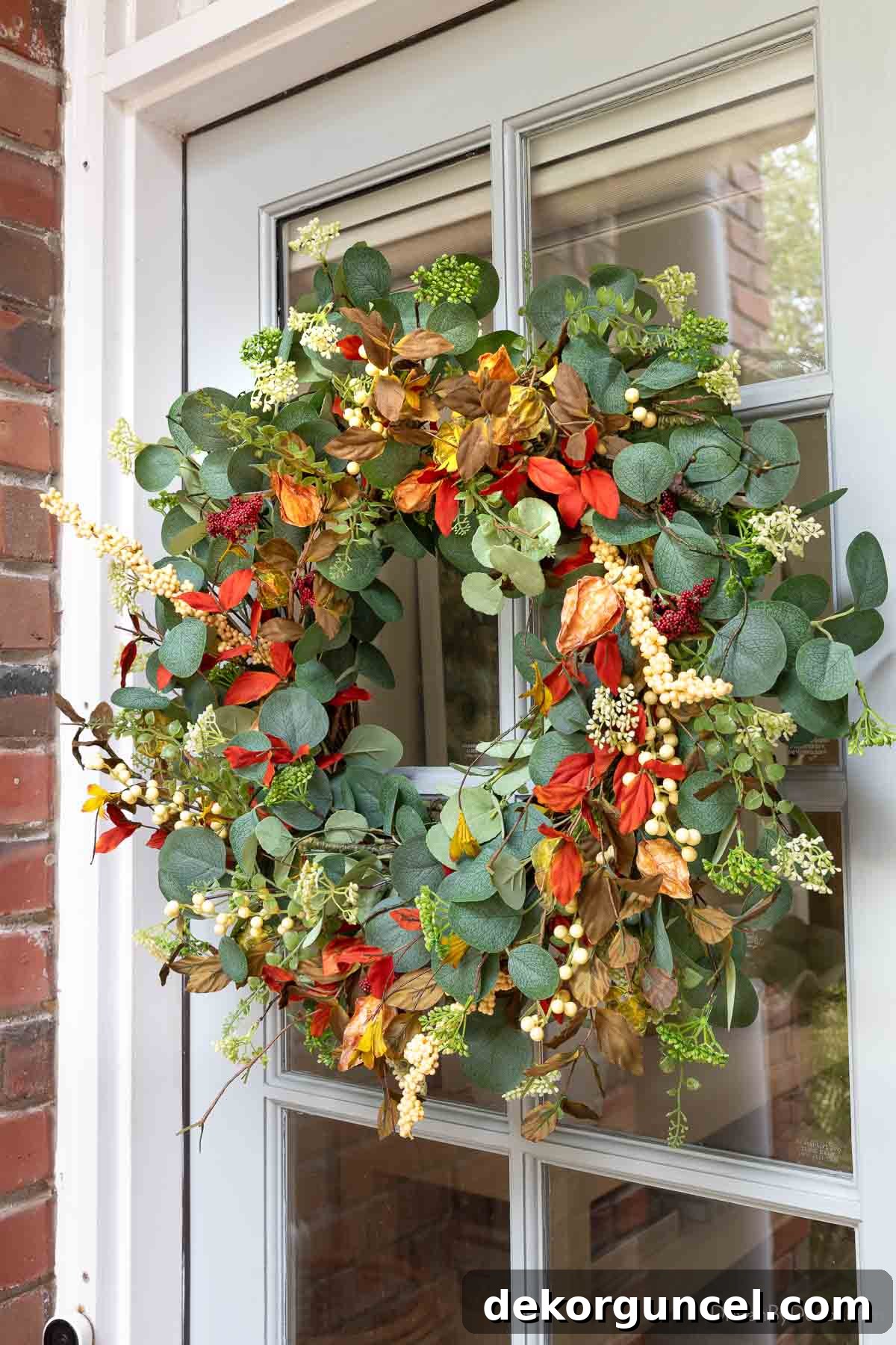 A colorful and inviting fall wreath featuring eucalyptus, elegantly displayed on a front door, offering great value for its beauty.