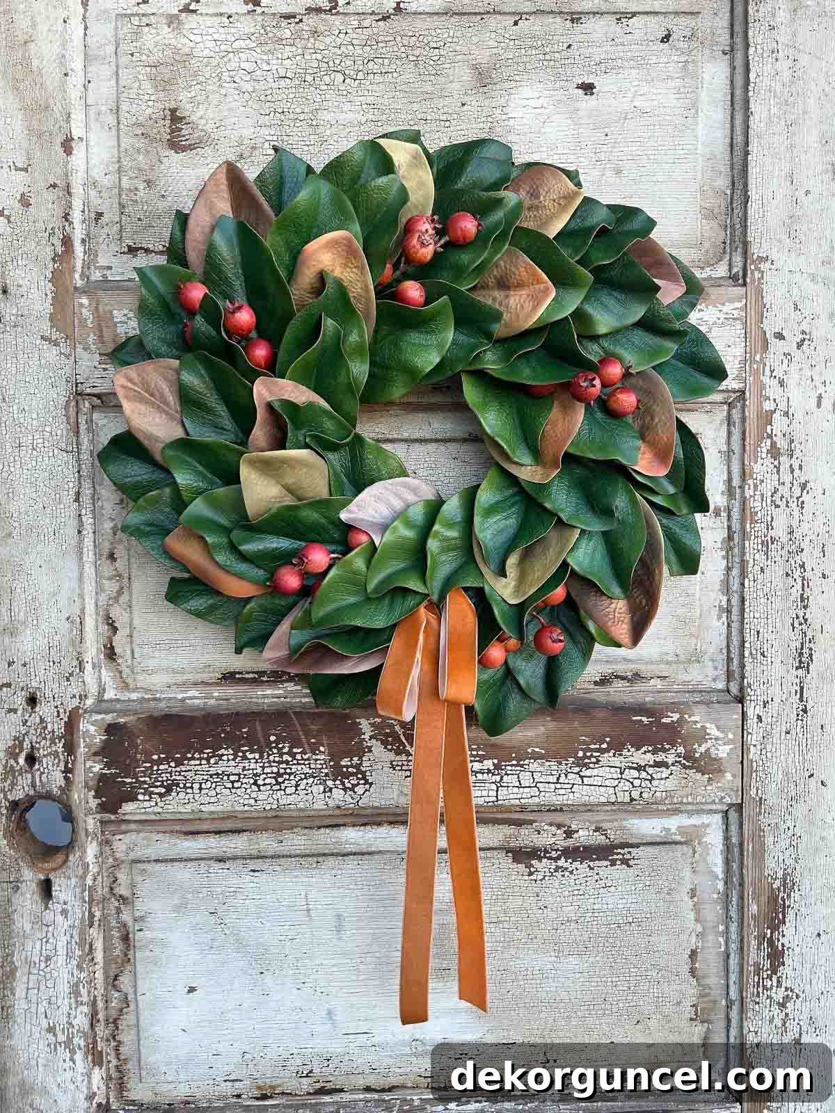 Stunning magnolia wreath lavishly adorned with berries and a rich velvet bow, creating an opulent fall and winter display.