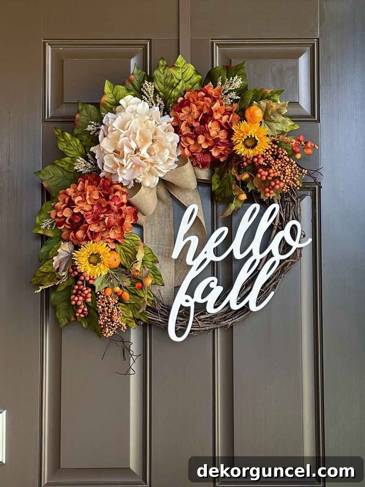 A rustic fall grapevine wreath featuring hydrangeas, sunflowers, and the welcoming script phrase 'hello fall'.