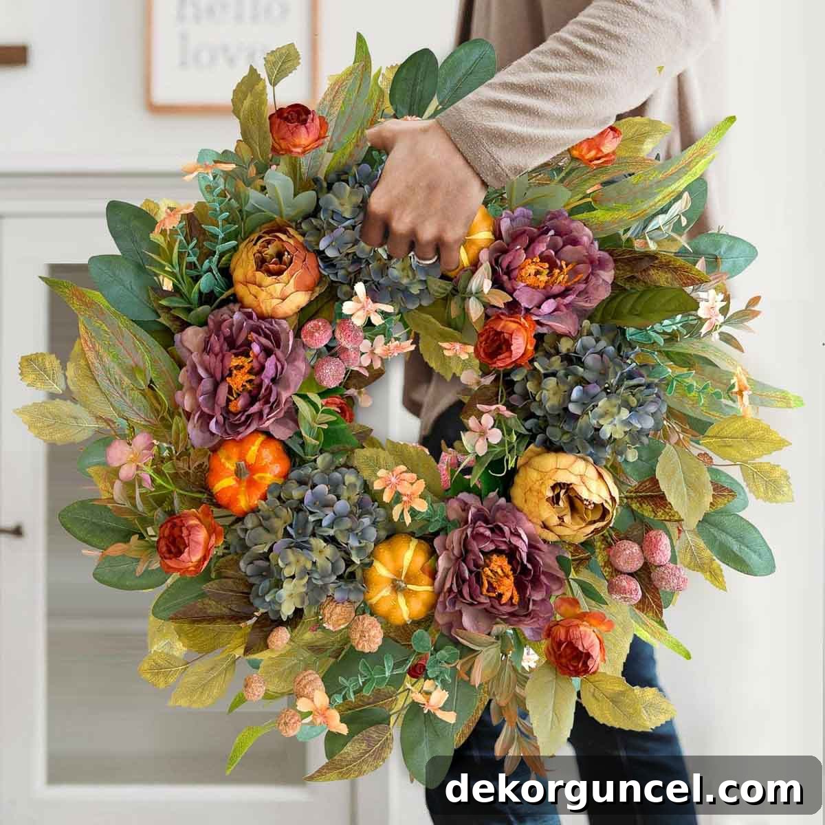 Affordable fall wreath showcasing a delightful mix of mini orange pumpkins and an assortment of vibrant seasonal flowers.