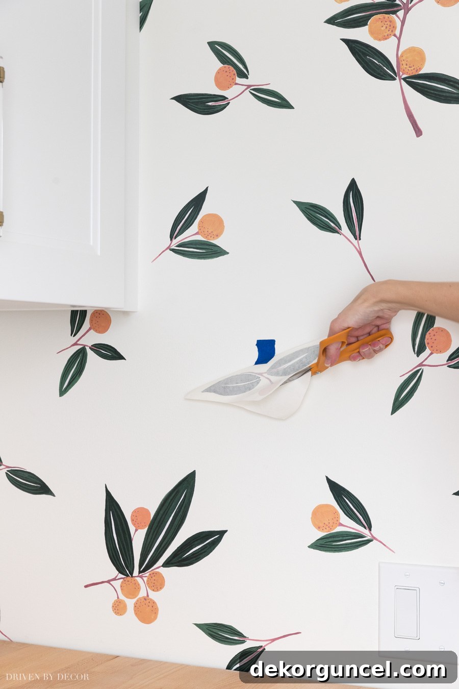 Detailed view of a vinyl wall decal with approximately one-third of its backing paper carefully removed, demonstrating the hinge application technique.