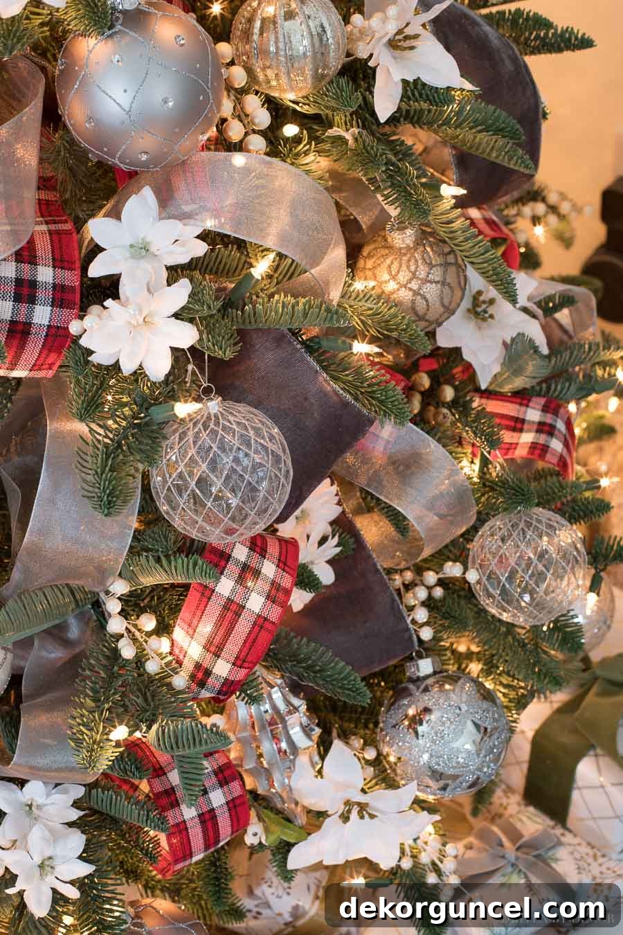 A beautifully decorated Christmas tree featuring a luxurious mix of wide gray velvet ribbon, cheerful red plaid ribbon, and subtle sheer silver accents.