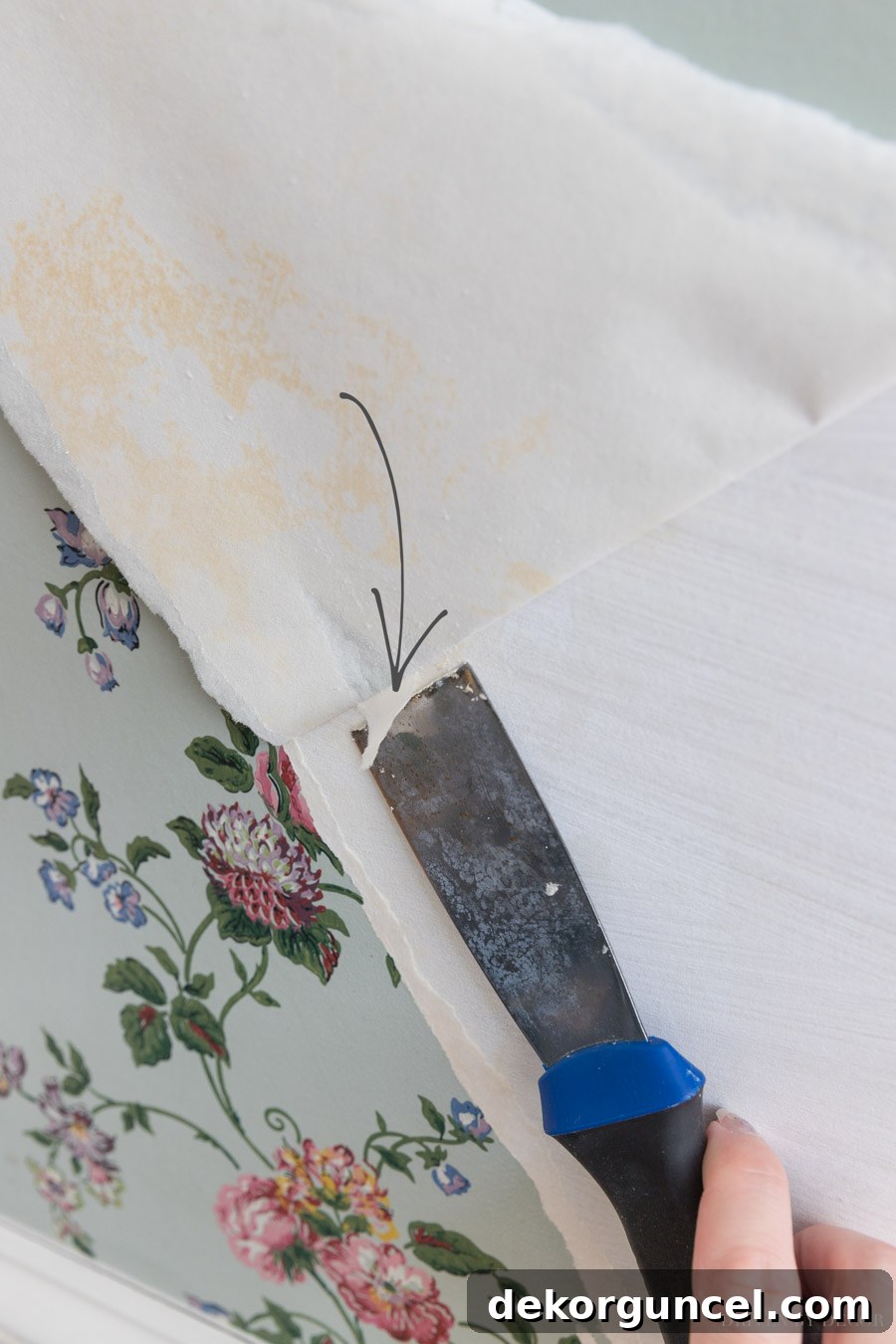 Efficient wallpaper removal: using a putty knife for stubborn paper backing