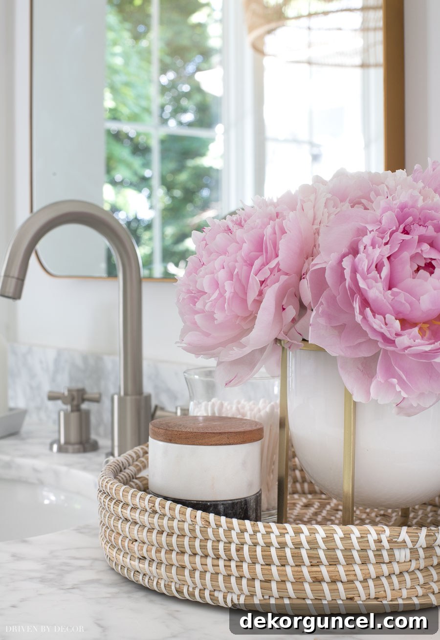 Small woven tray perfectly nestled between the double sinks, holding decorative and essential items