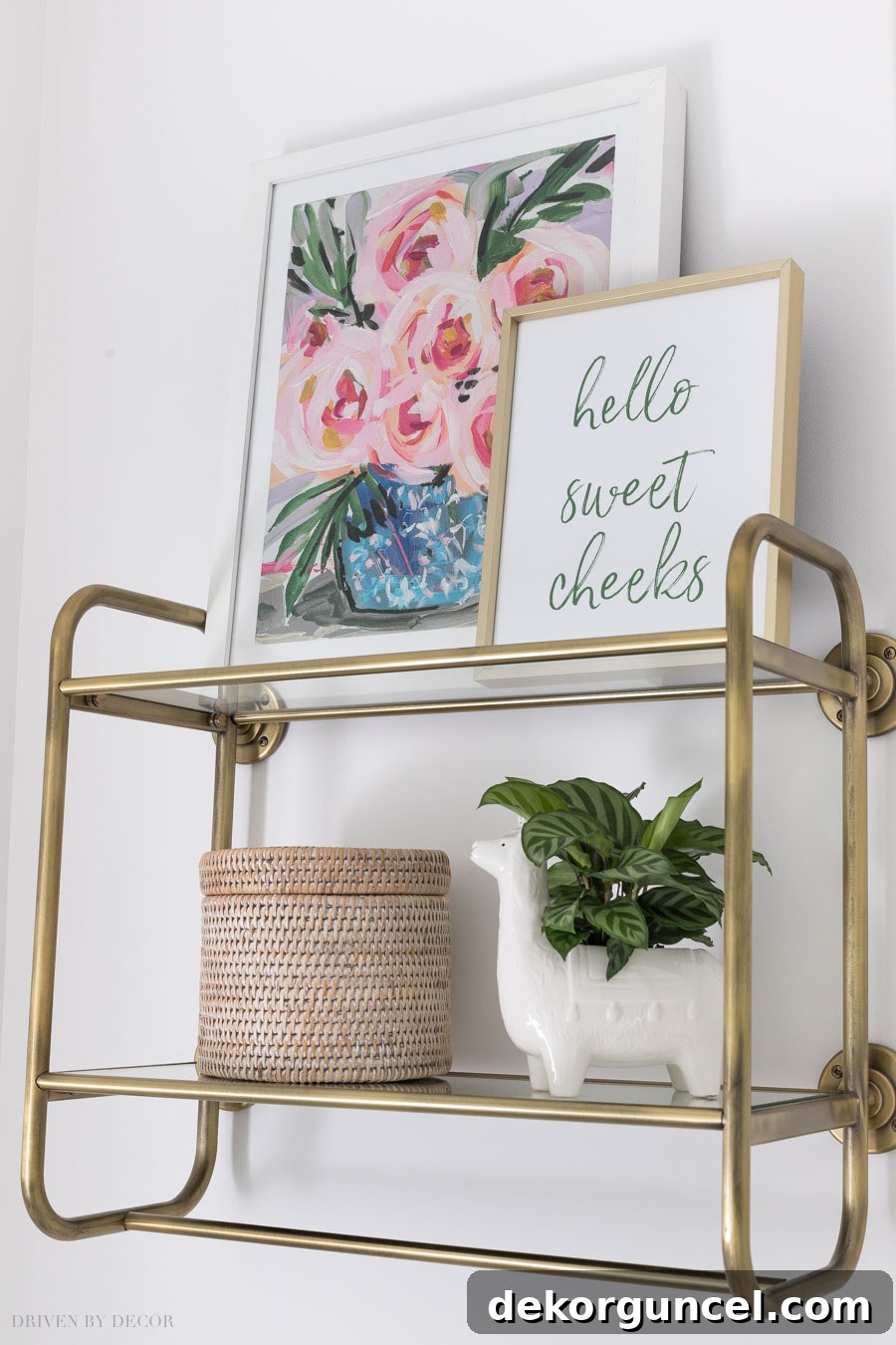 A stylish brass wall shelf above the toilet, holding decor and providing a hanging bar