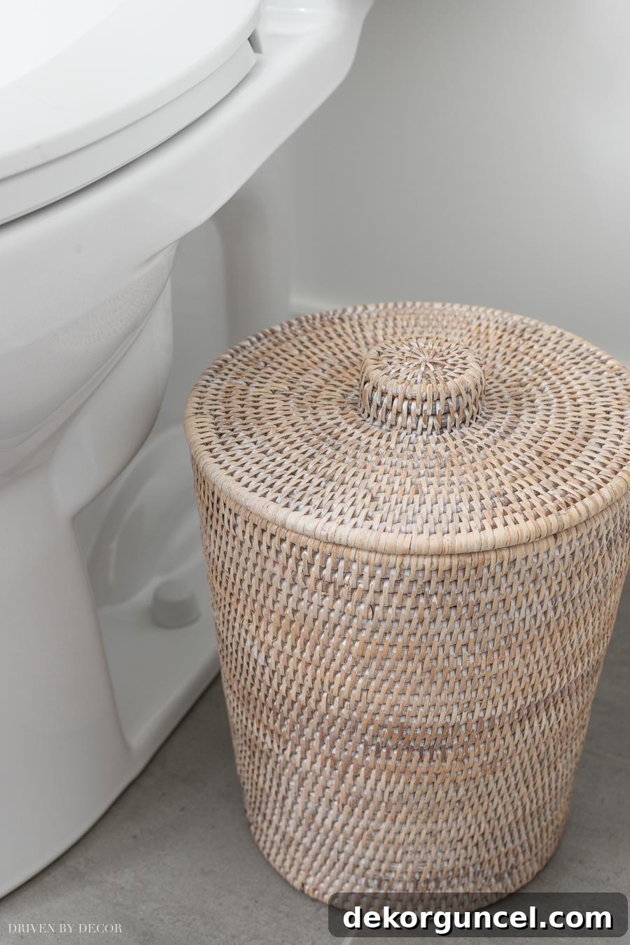 A cute rattan trash can, complete with a plastic liner, blending seamlessly with the bathroom decor