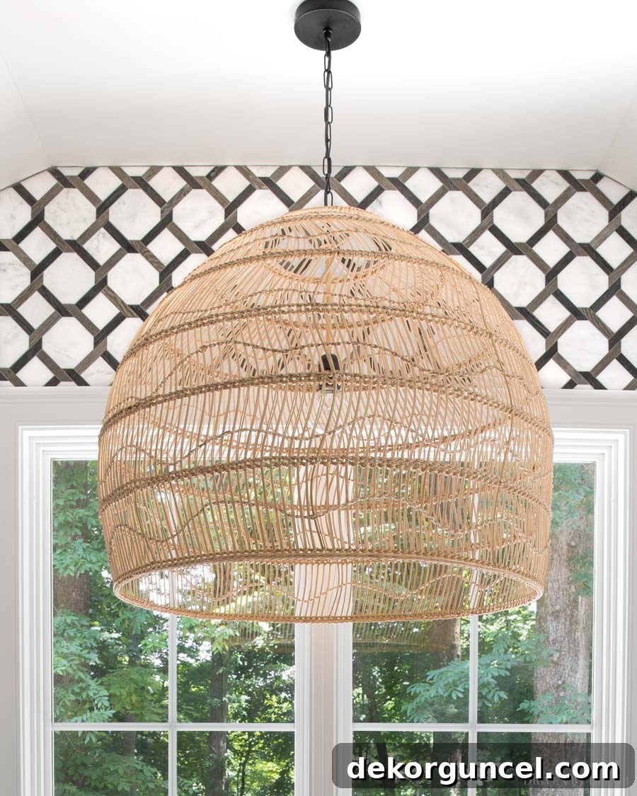A large, open-weave rattan pendant light gracefully hanging above the bathtub in the master bathroom