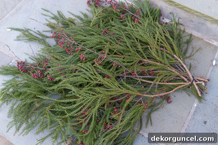 Layering greenery and berry branches to create a Christmas front door swag