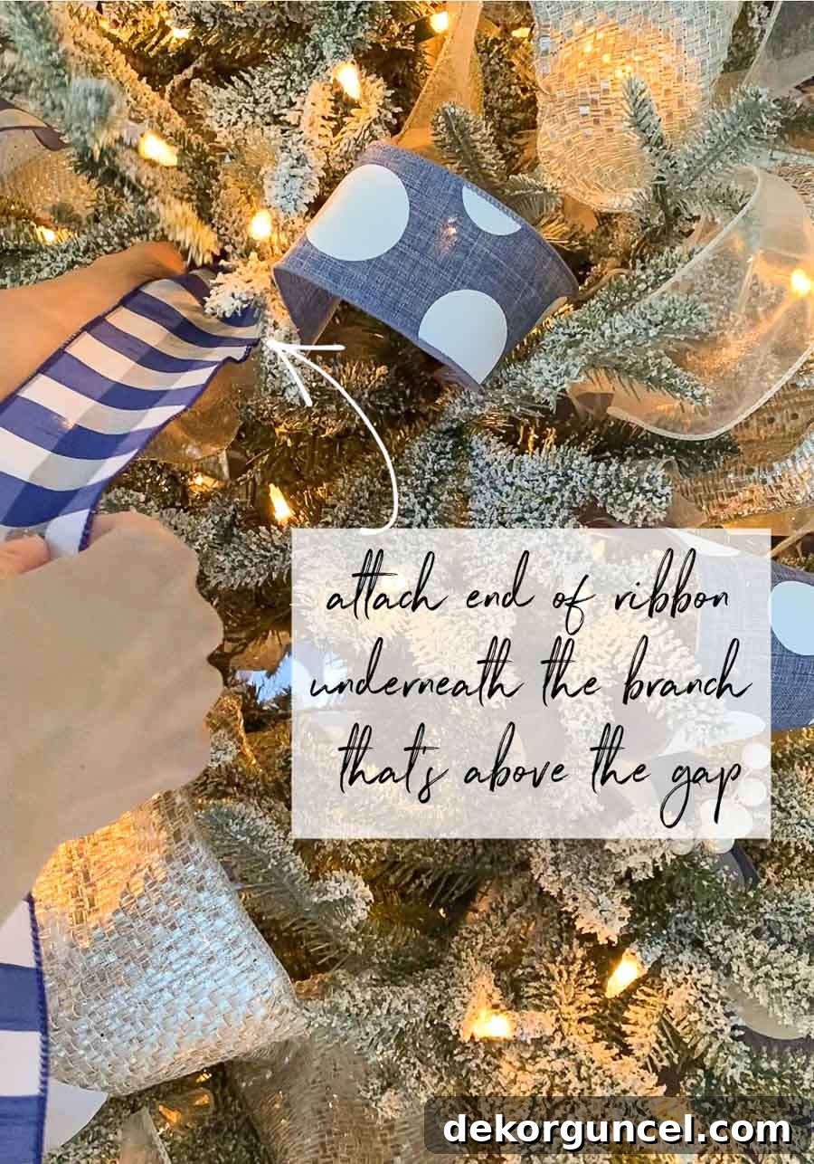 The Ultimate Christmas Tree Decorating Guide 13 Attaching the start of the ribbon to a tree branch.