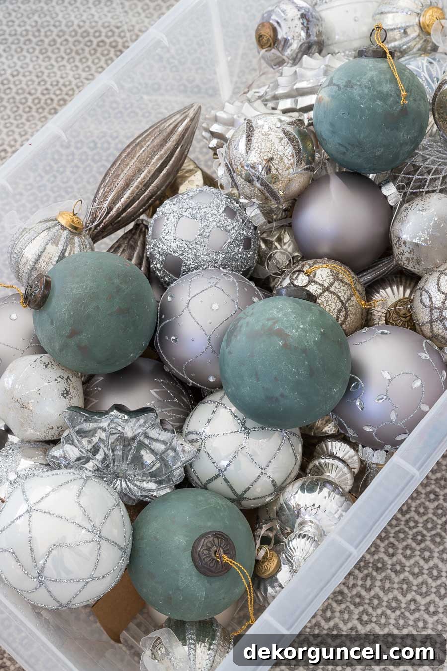How to Perfectly Flock a Christmas Tree 11 A vibrant collection of gold, silver, and green Christmas ornaments, beautifully unwrapped and ready to adorn a freshly flocked Christmas tree, promising a stunning festive display.