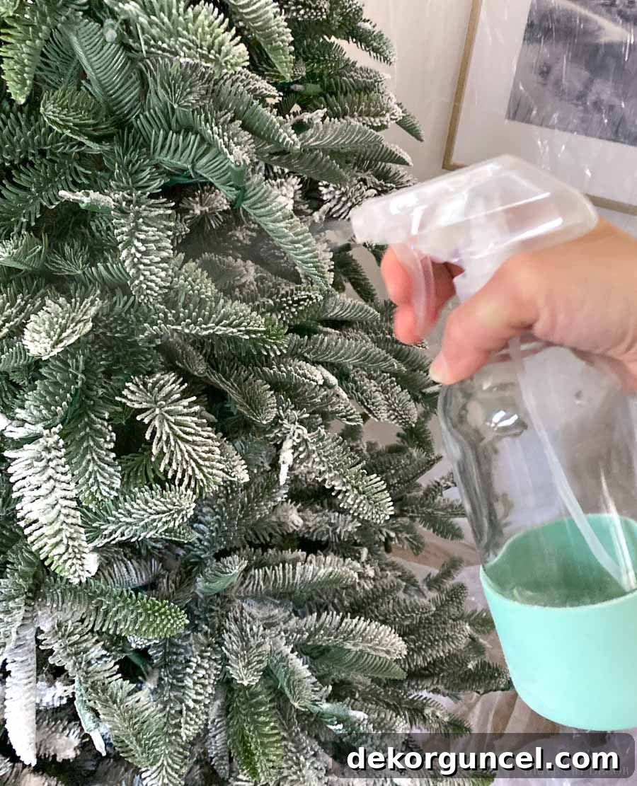 How to Perfectly Flock a Christmas Tree 8 The crucial final step in flocking a Christmas tree: a thorough misting with water to seal and permanently set the flocking powder, ensuring a durable and beautiful snowy finish.