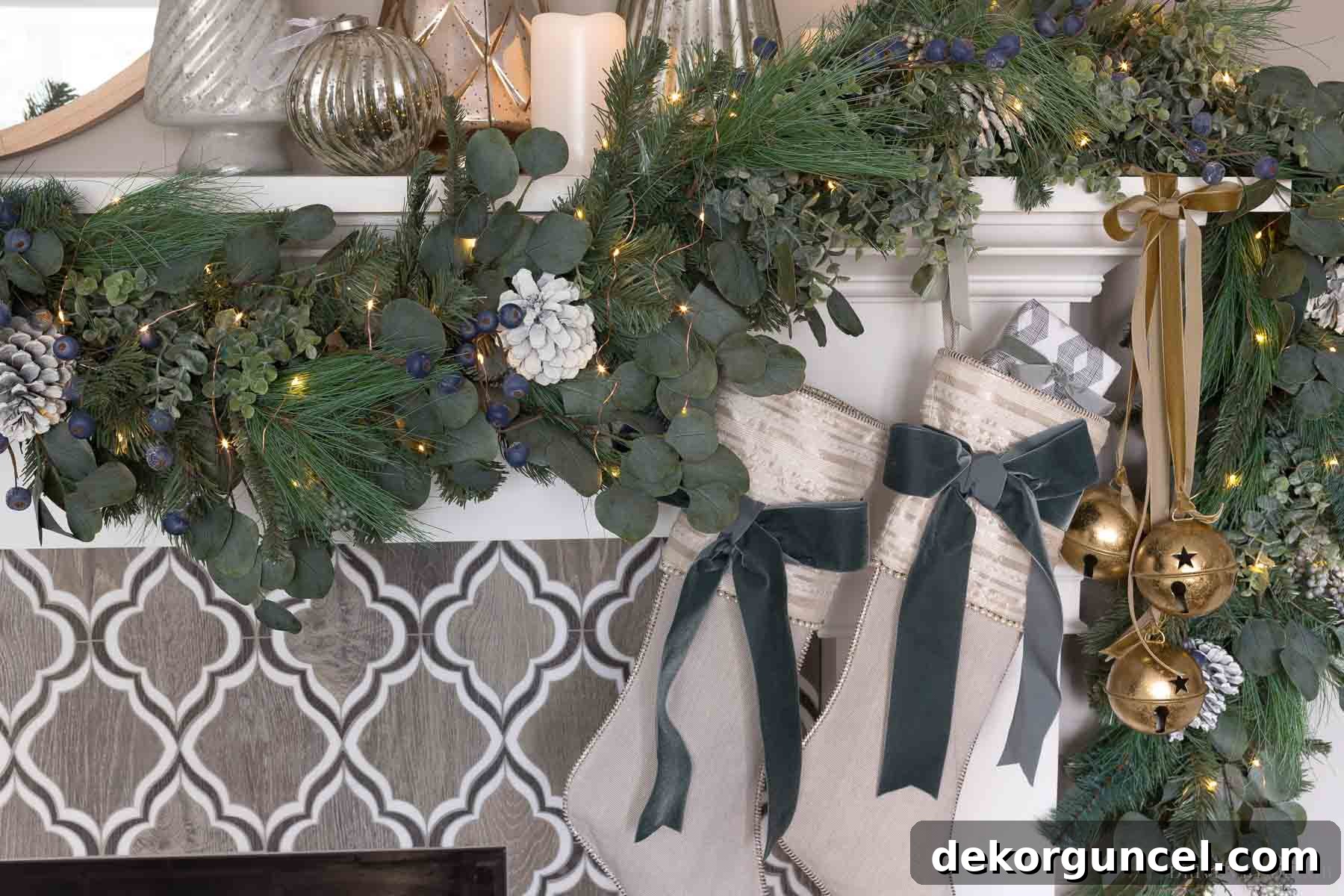 Our fireplace mantel, exquisitely decorated for Christmas, featuring a festive greenery swag, hanging stockings, large gold jingle bells, and an array of mercury glass trees.