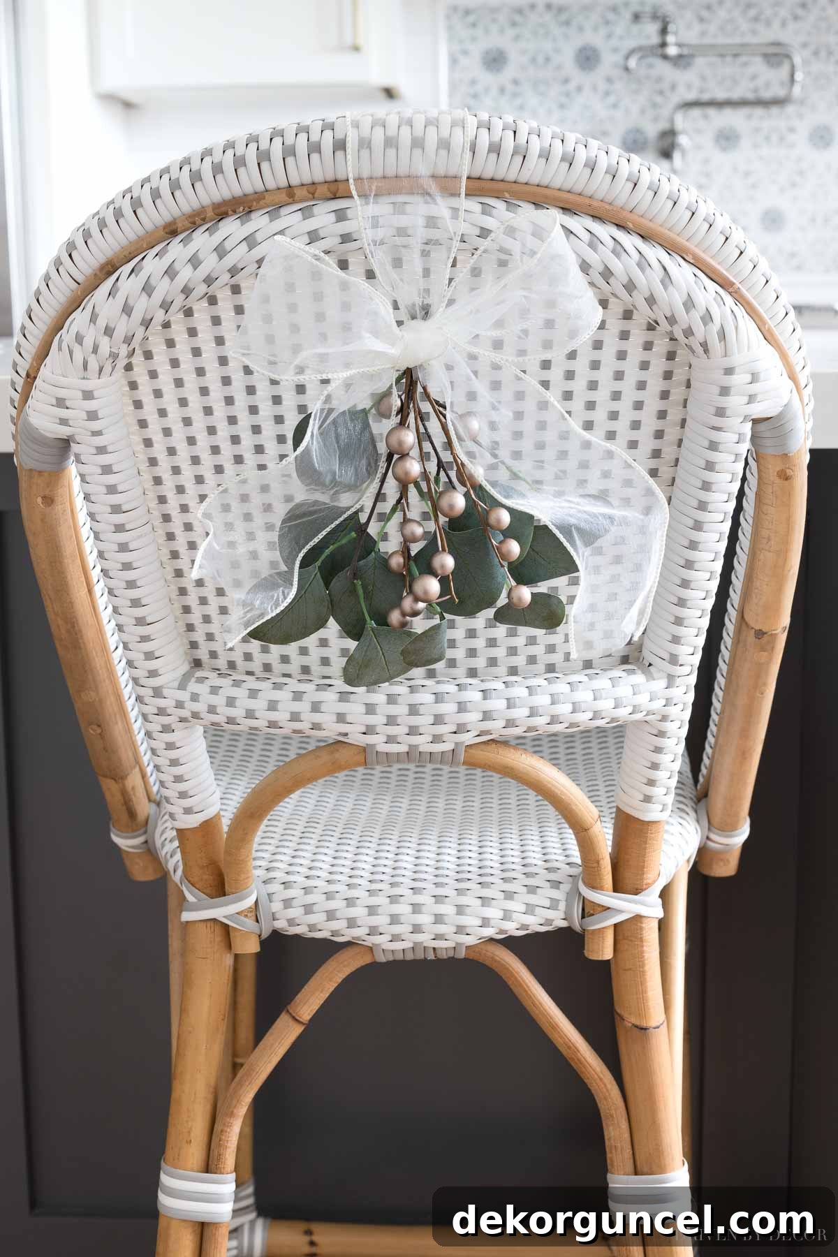 Adorable mini greenery swags, elegantly tied with bows, serve as perfect simple Christmas decorations, adding festive charm to the backs of our kitchen chairs.
