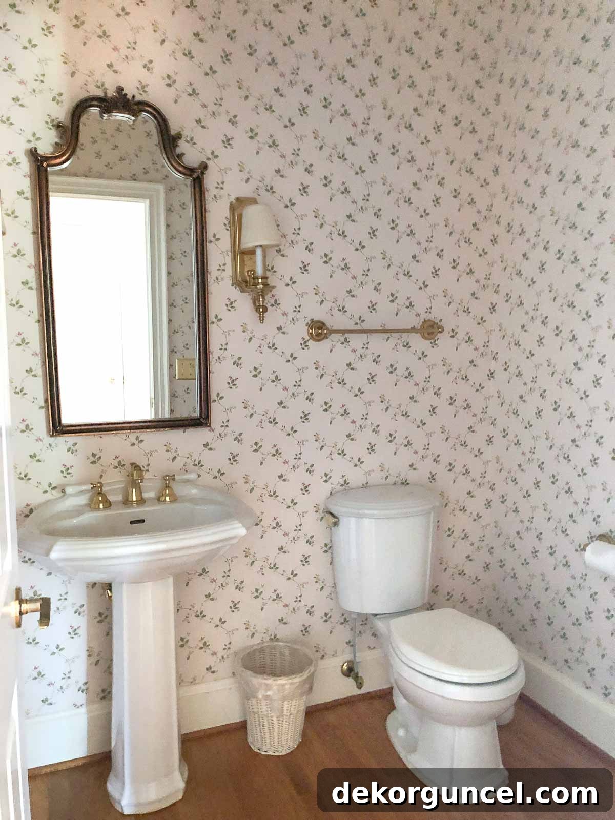 Our hall bathroom before remodeling - featuring a pedestal sink, arched mirror, and dated floral wallpaper, awaiting transformation