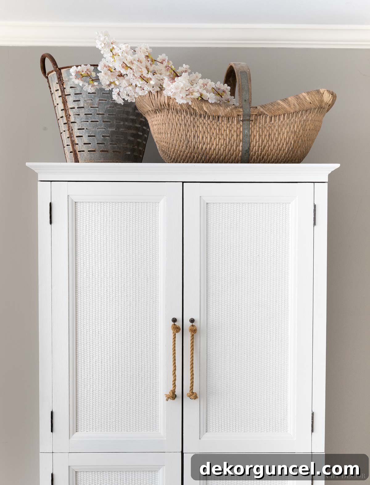 The Most Realistic Faux Flowers 11 Realistic artificial cherry blossom branches elegantly arranged in a woven basket atop an armoire, creating a charming focal point and adding softness to a room's decor.