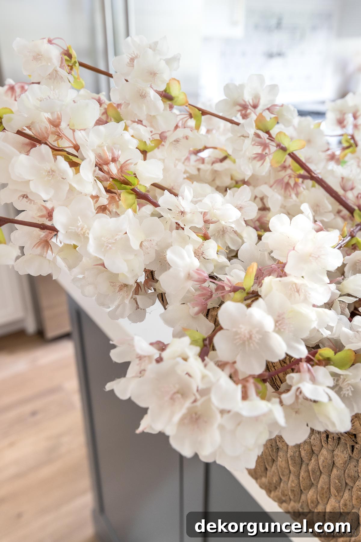 The Most Realistic Faux Flowers 13 A close-up of exceptionally realistic artificial cherry blossoms filling a vase in a dining room, showcasing their vibrant and lifelike petals and delicate branches, perfect for elegant home decor.