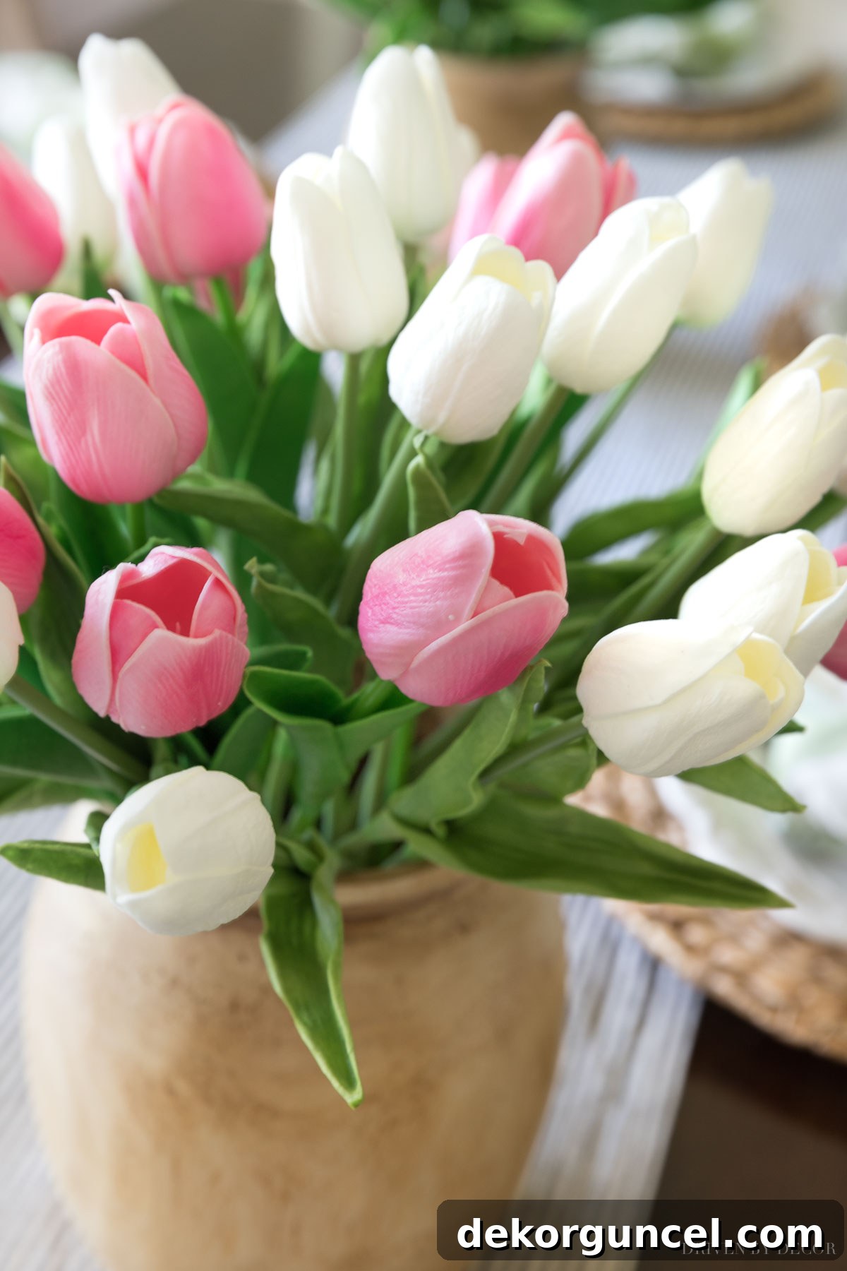 The Most Realistic Faux Flowers 5 Stunningly realistic artificial tulips, both pink and white, elegantly arranged in beautiful wooden vases as a key part of a sophisticated spring dining room decor, creating a fresh ambiance.