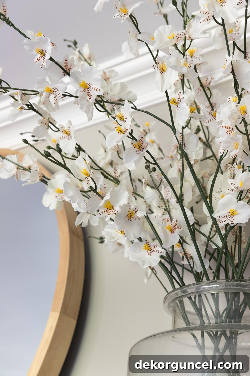 The Most Realistic Faux Flowers 7 A close-up of elegant faux white orchids meticulously arranged in clear glass vases, adding a refined and serene touch to a fireplace mantel in a modern living room.