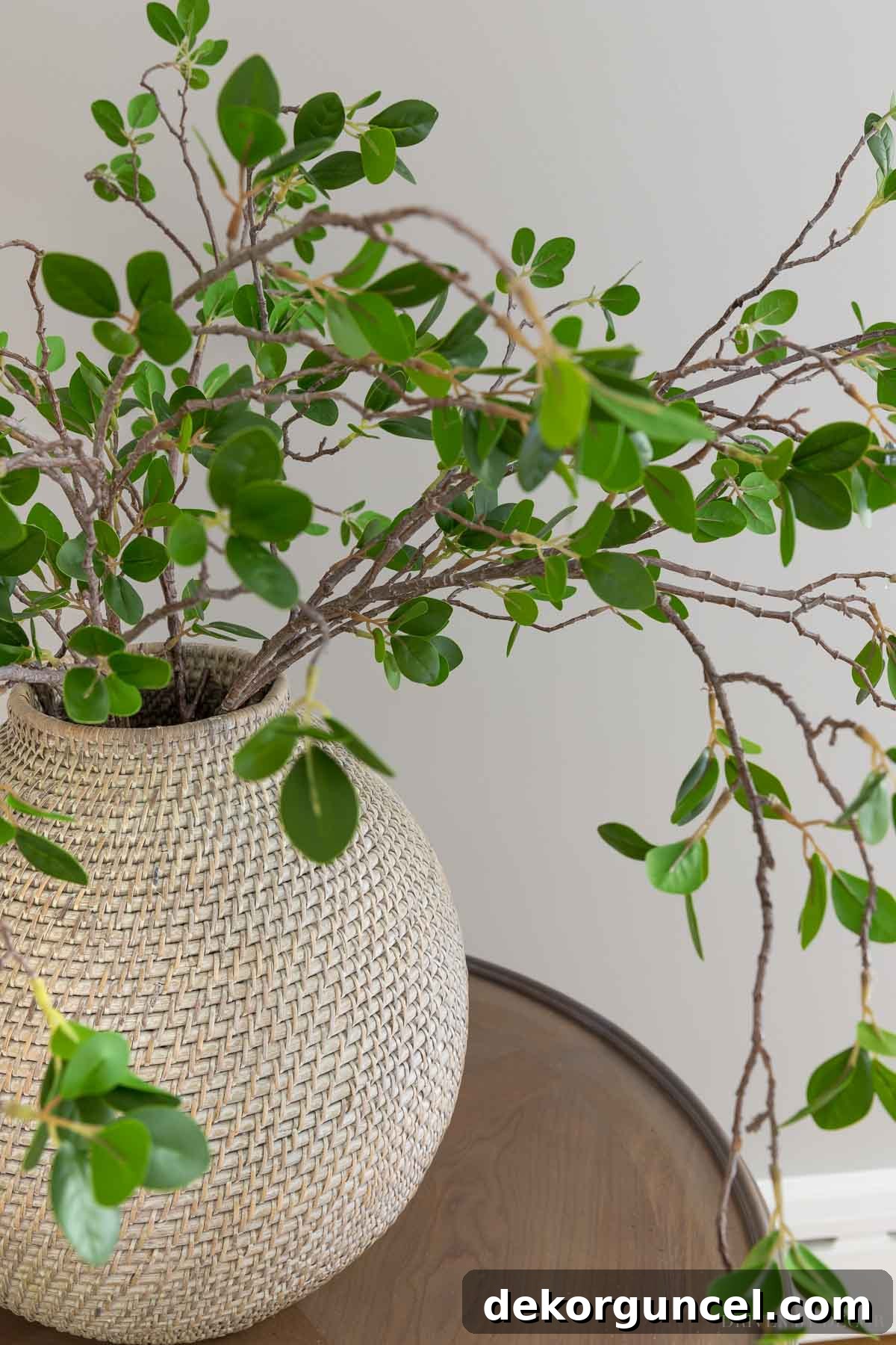 The Most Realistic Faux Flowers 9 A large bamboo vase filled with a set of five realistic faux leafy greenery branches, adding natural beauty and a lush feel to a living room corner, complementing the existing decor.