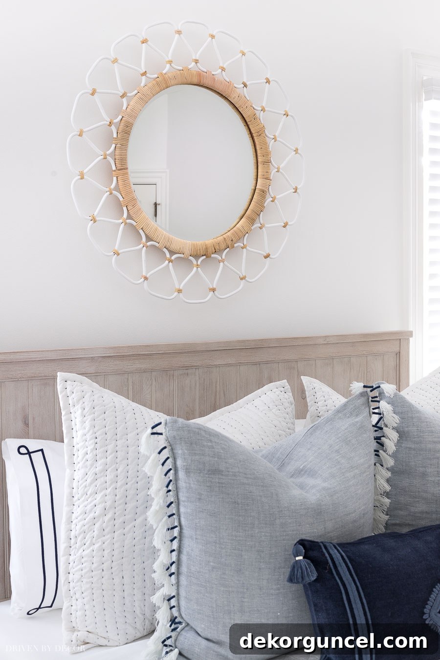 Two-toned decorative rattan mirror enhancing the above bed decor in a tranquil guest room setting.