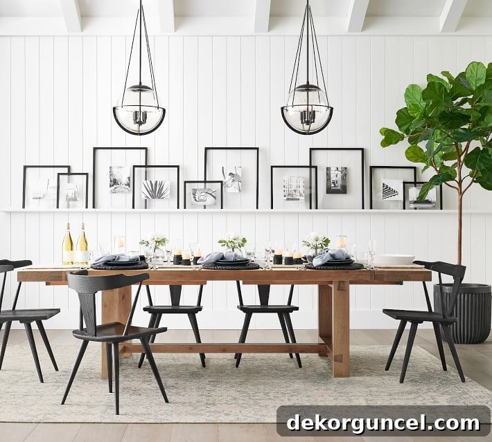 An elegant art ledge running the length of a dining room wall, showcasing a beautifully layered arrangement of framed photographs and art as dynamic wall decor.
