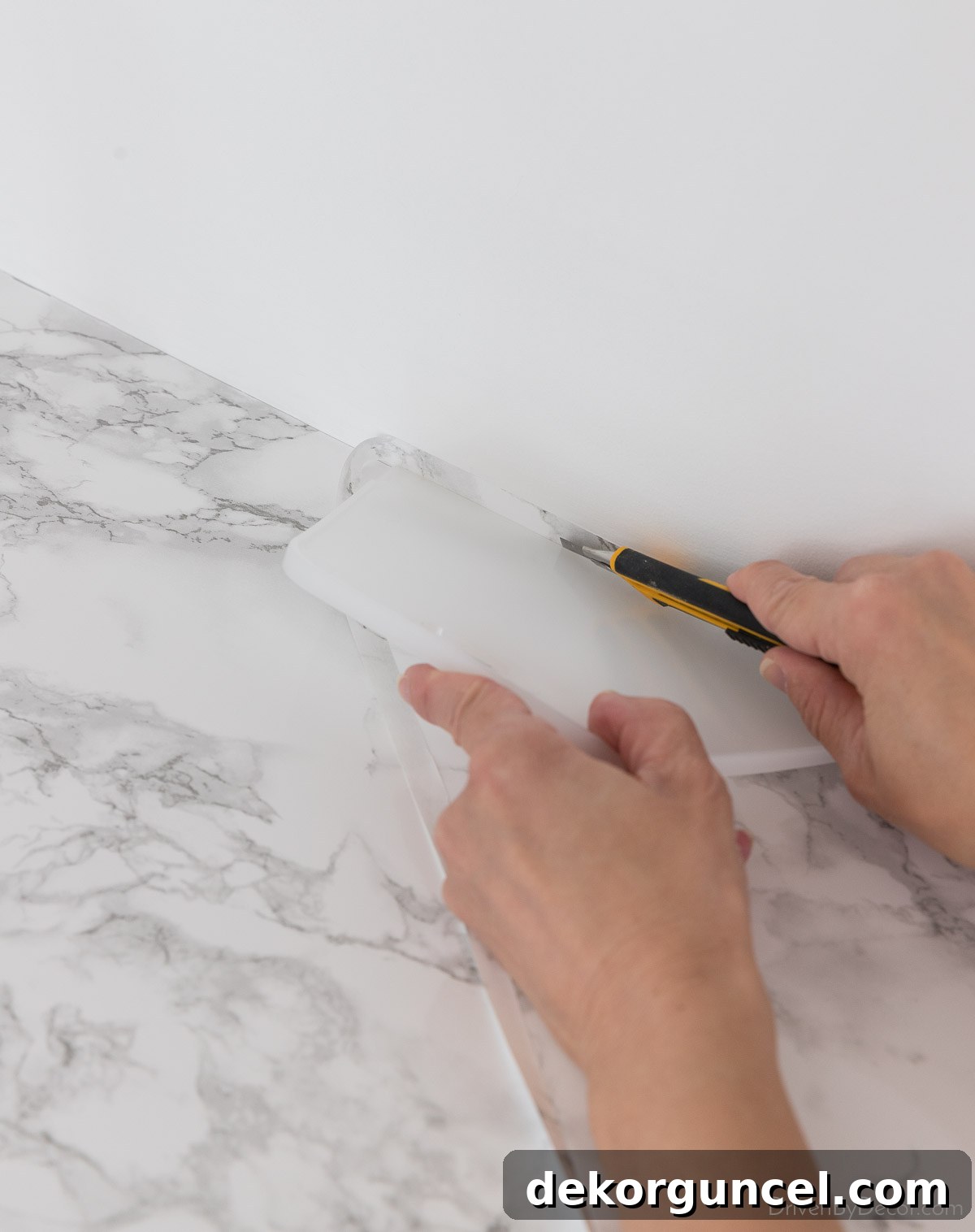 Using a smoothing tool and utility knife for clean cuts of marble contact paper