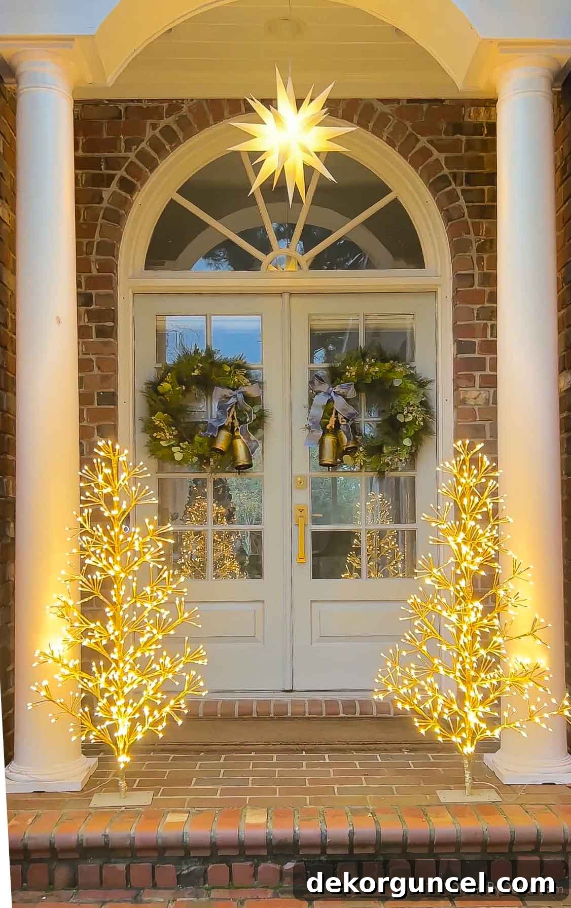 Outdoor Christmas decorations featuring a Moravian star and twinkling LED trees on a front porch