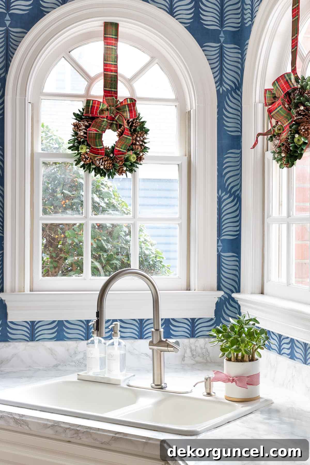 Miniature Christmas wreaths layered over kitchen windows, creating a charming festive look