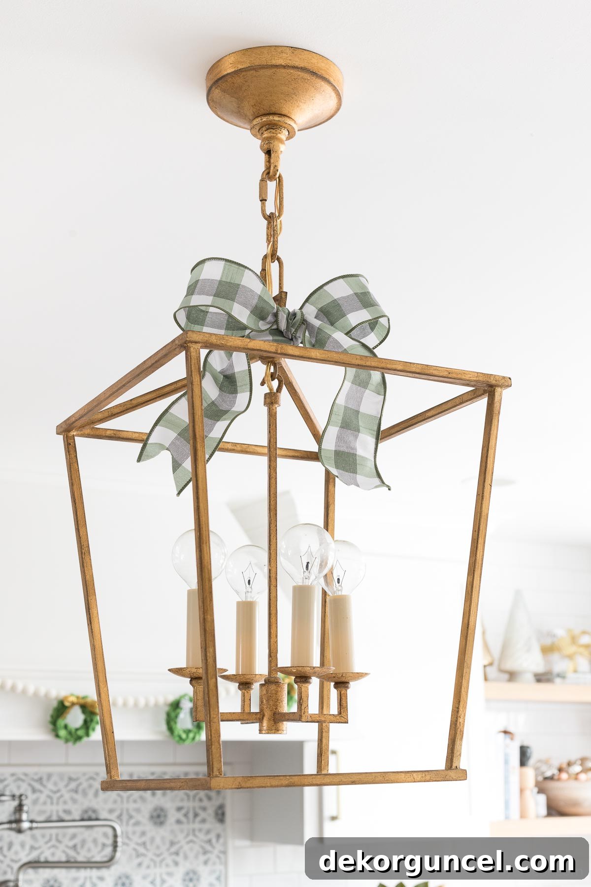Gold open pendants above a kitchen island decorated with simple plaid bows for Christmas