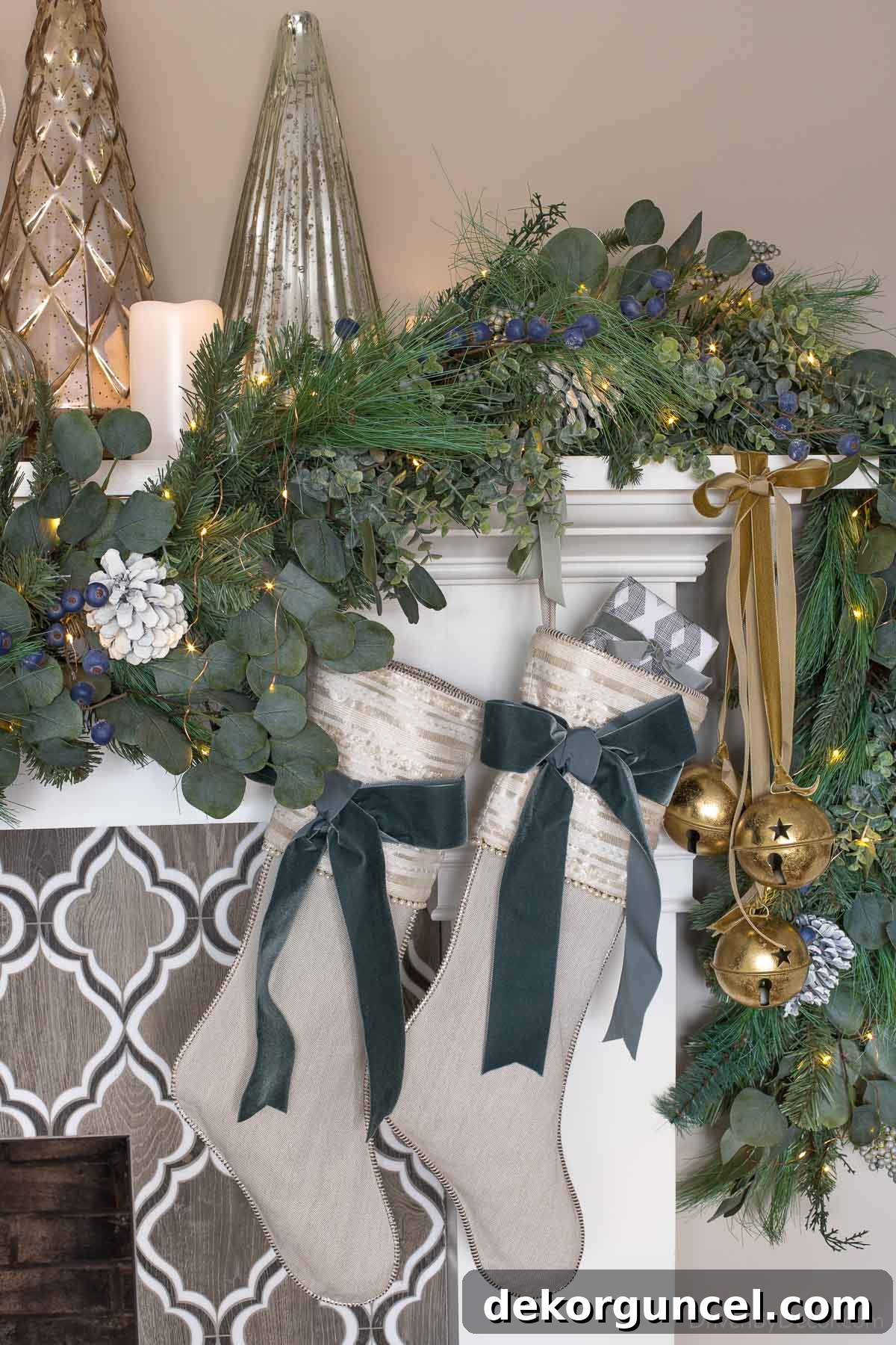 Fireplace mantel decorated with lush greenery, metallic trees, and battery-operated candles and twinkle lights
