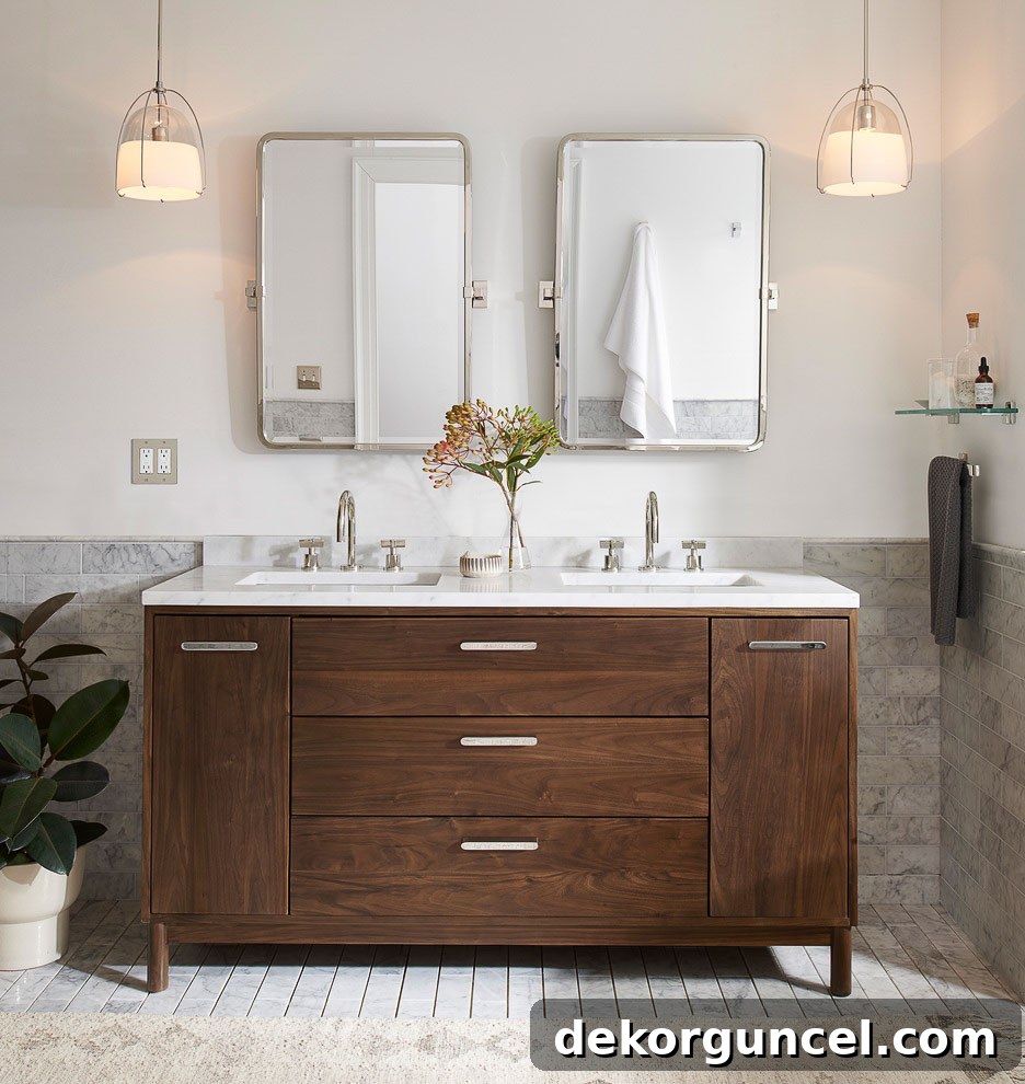 Small glass dome pendants elegantly flanking a double walnut vanity, offering a modern alternative to traditional sconces for bathroom lighting.