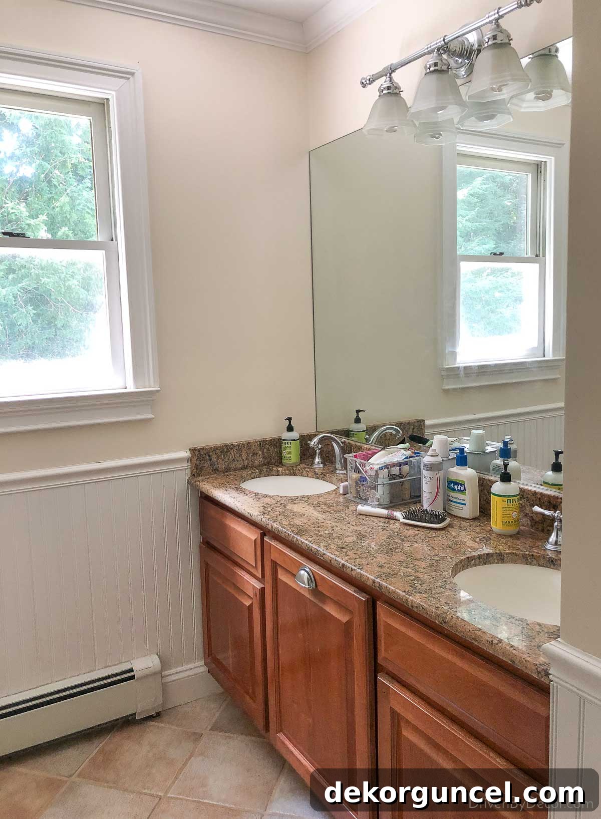 An old-fashioned bathroom vanity light with dated glass shades before renovation.