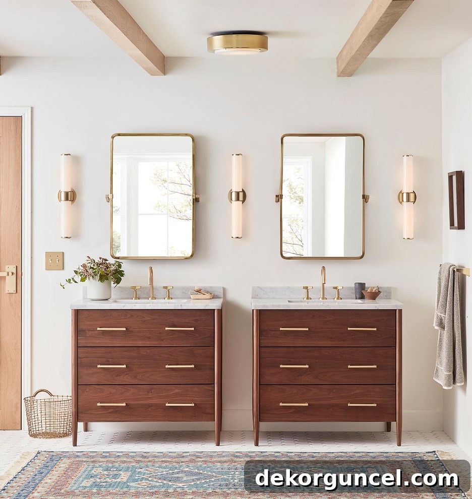 A master bathroom featuring two separate vanities unified by a harmonious arrangement of three sconce lights, two flanking the outer edges and one centered between them.