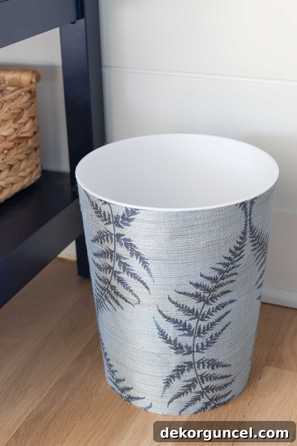 An ordinary waste basket beautifully transformed with a grasscloth wallpaper remnant, adding texture and sophistication