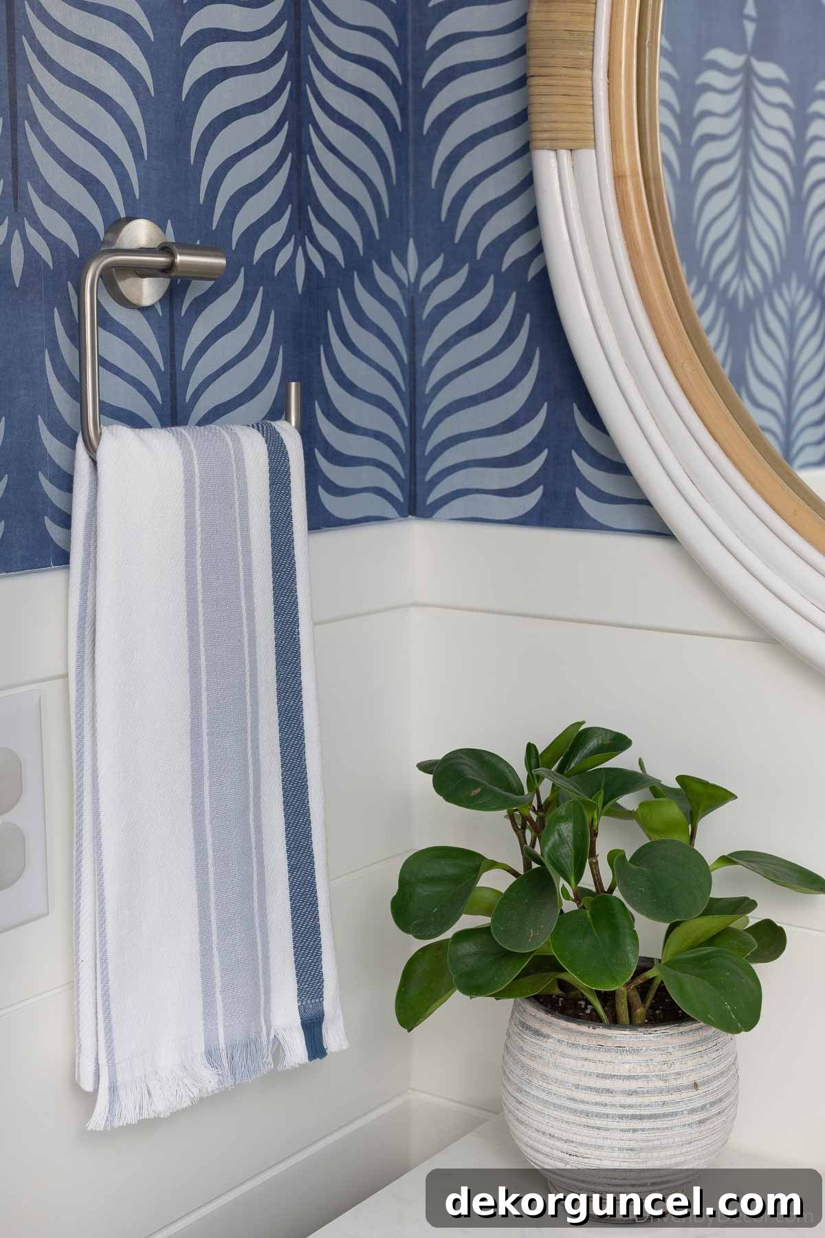 A modern stainless steel towel ring holding a stylish blue striped hand towel, adding both function and a splash of color