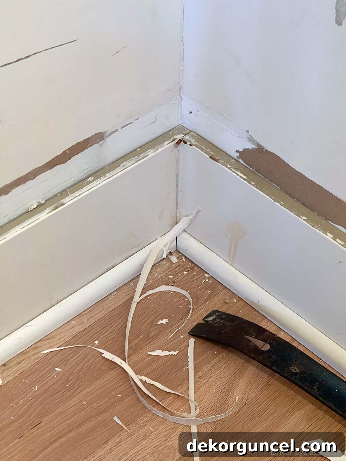 Our baseboards in the powder room prior to the installation of bathroom shiplap, showing the clean edge after cap removal