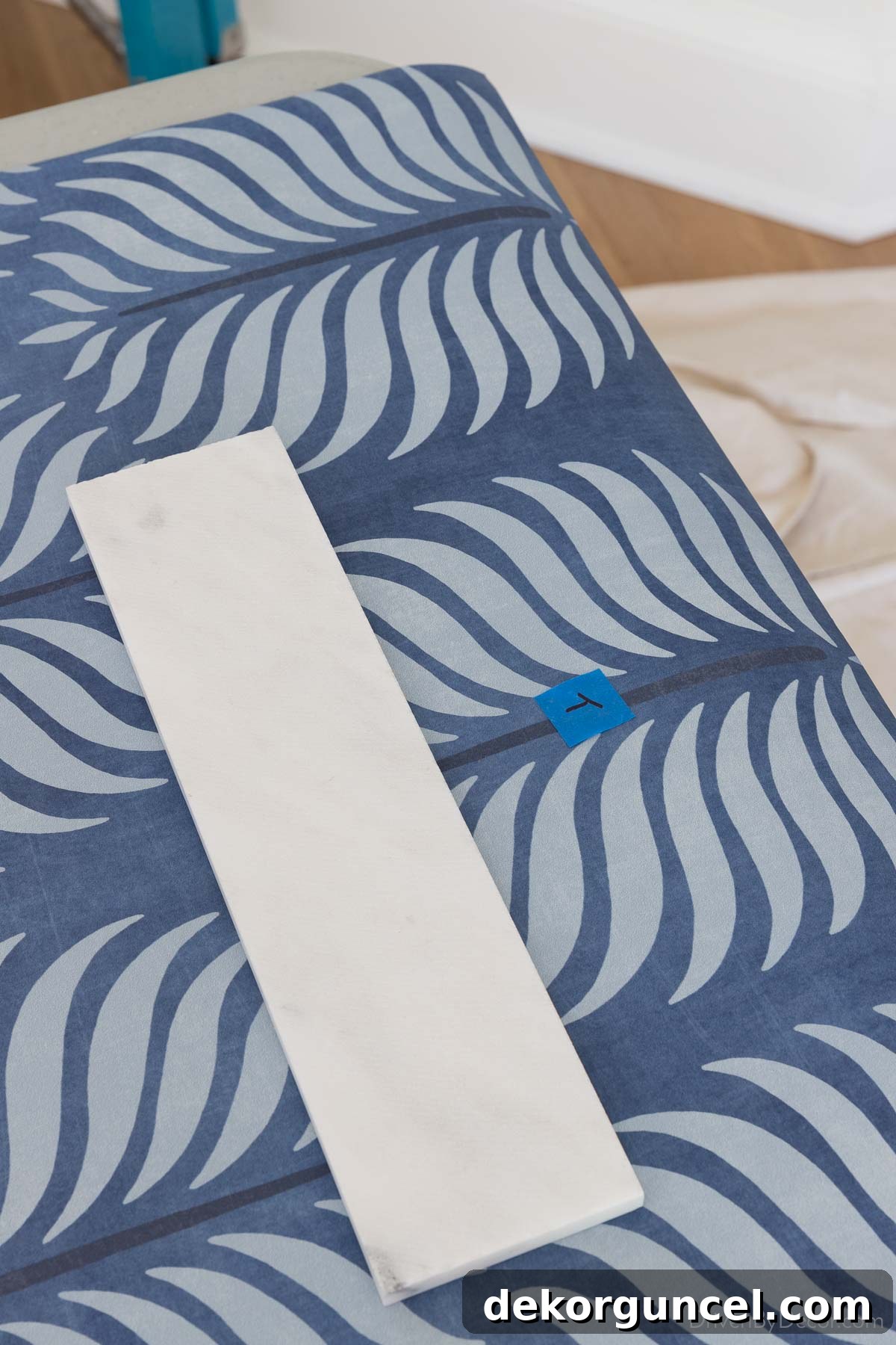 A piece of painter's tape clearly labeling the top of a wallpaper strip, preventing confusion during installation.