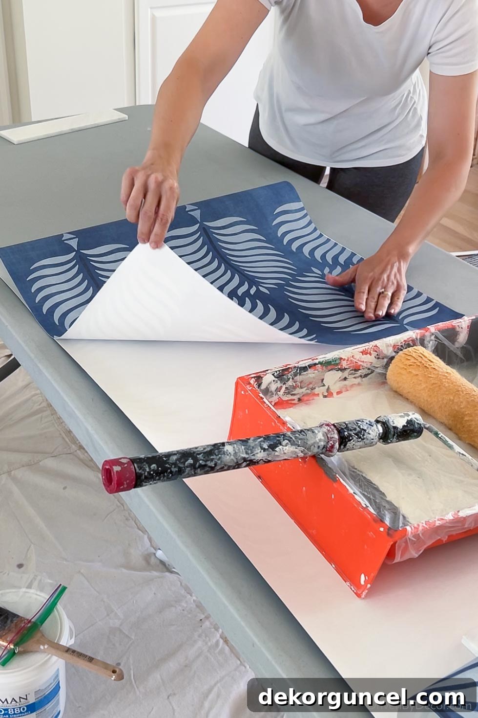 Gently folding over the pasted top half of a wallpaper strip without creasing, preparing for booking.