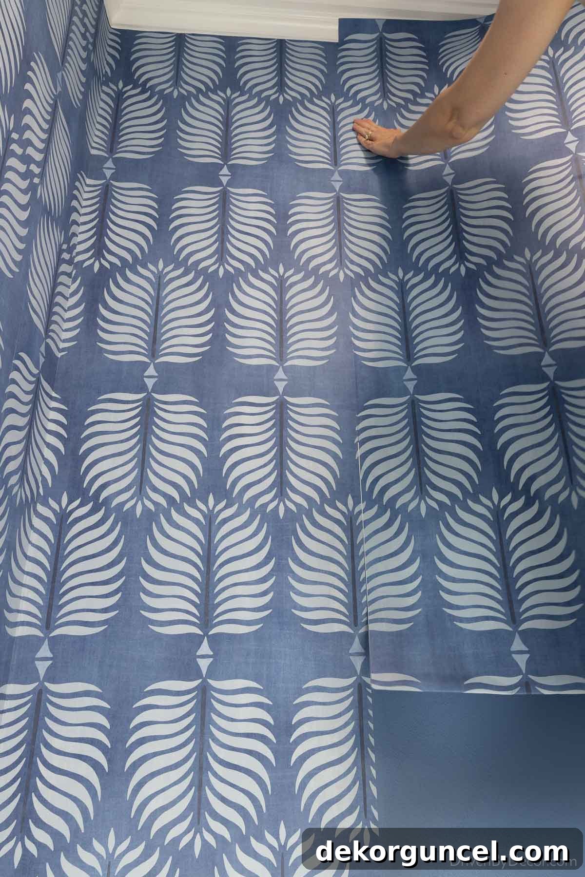 Demonstration of matching up wallpaper patterns and setting the seam, with one side held away from the wall for precision.