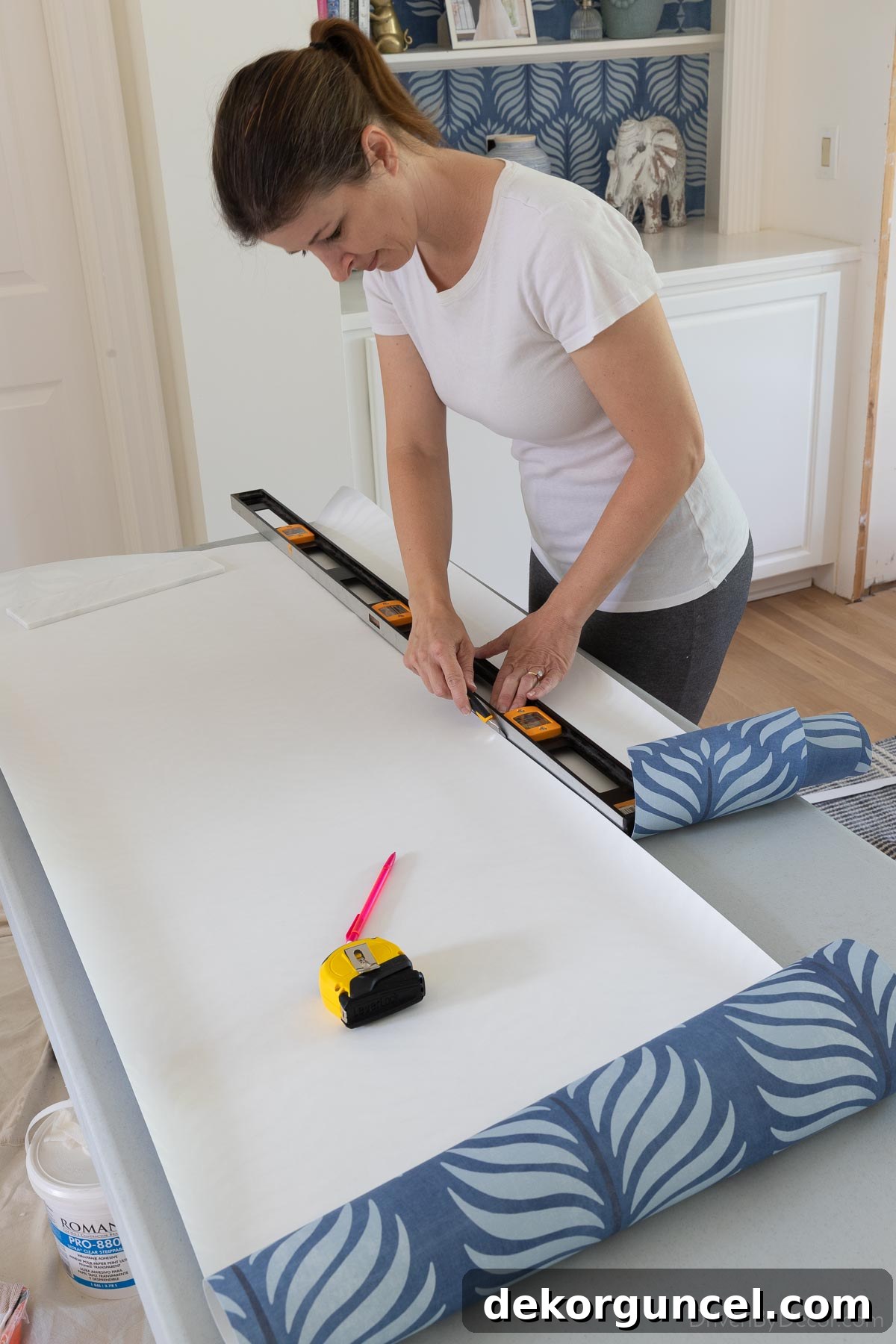 Cutting a wallpaper strip lengthwise into two pieces for proper installation around an interior corner, showing precise measurements.
