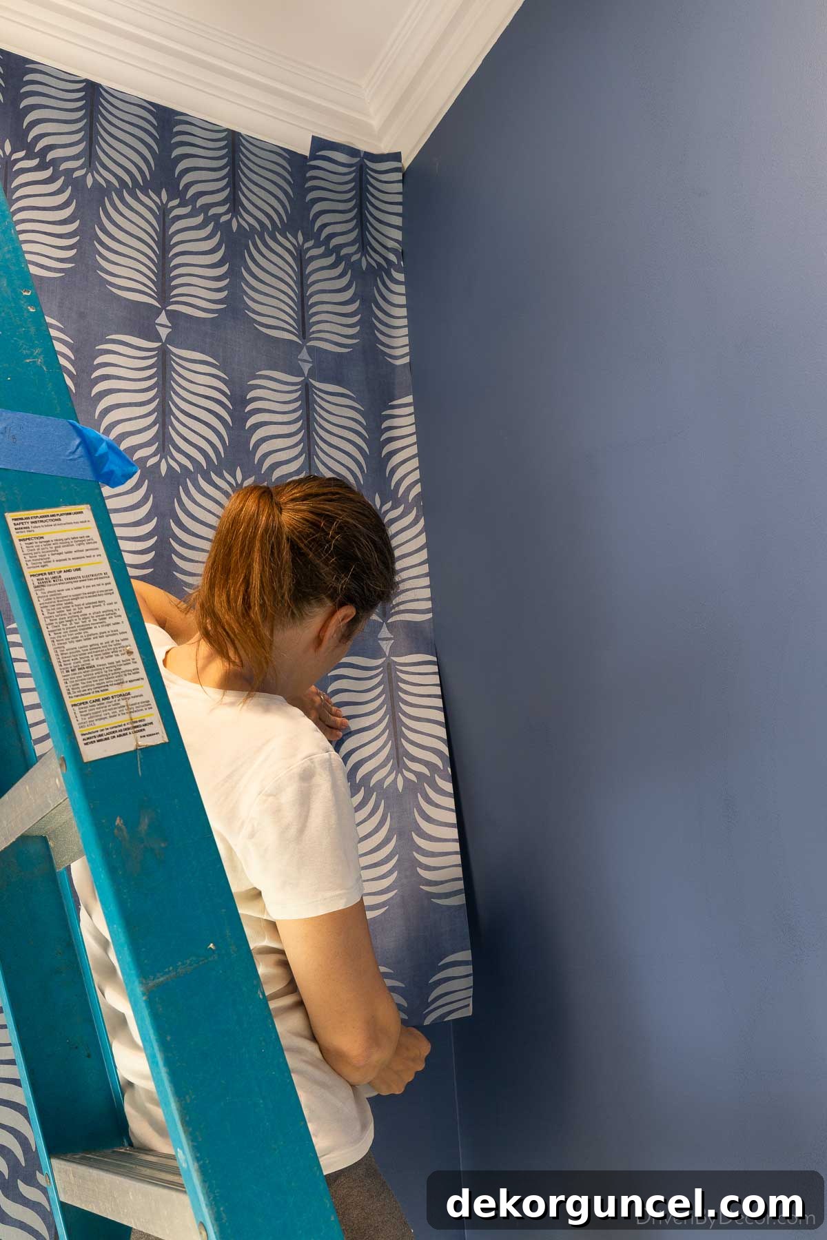 Installing a narrow wallpaper strip into an interior corner, carefully pressing it for smooth adhesion and proper overlap.