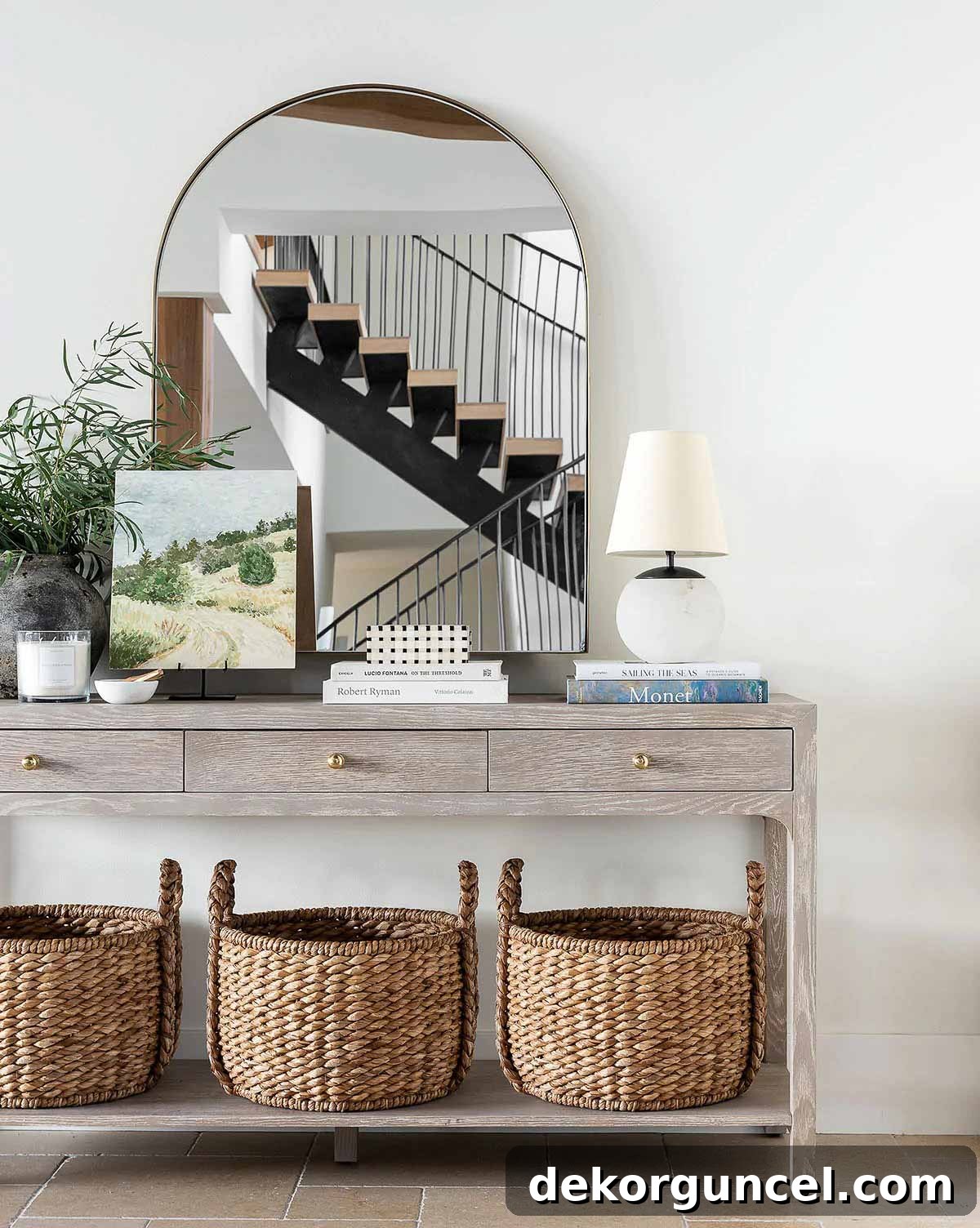 Arched mirror over a console table with woven baskets on the bottom shelf