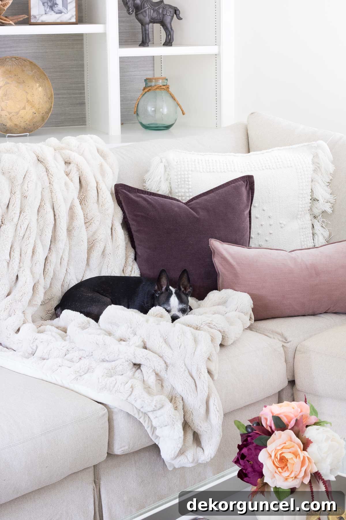 A cozy faux fur throw and velvet pillows on sofa for fall